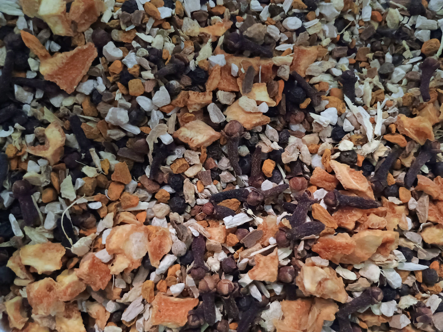 Mixture of dried herbs and spices including orange peels, black tea leaves, and white flowers.