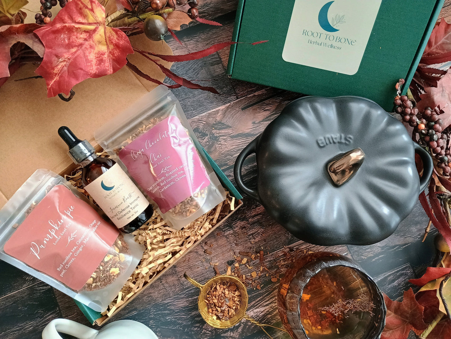 Decorative items including a black pot, small bottles, and a box on a wooden surface with autumn leaves.