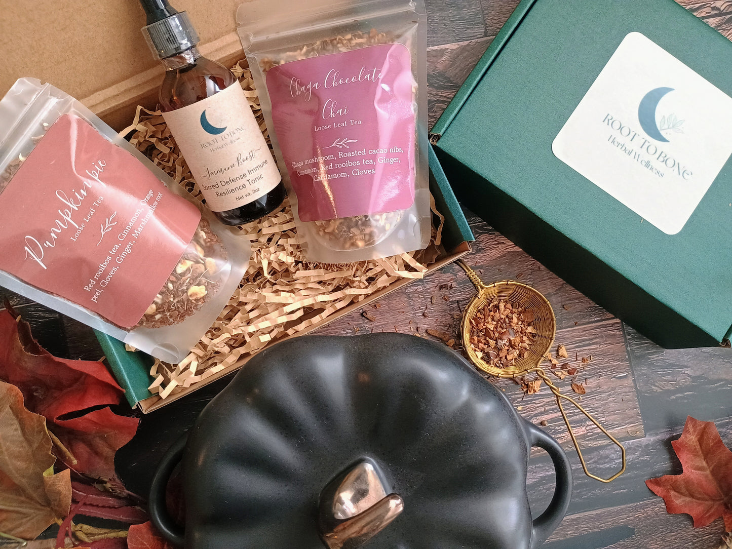 Gift set with tea, chocolate, and a pumpkin-shaped pot on a wooden surface.