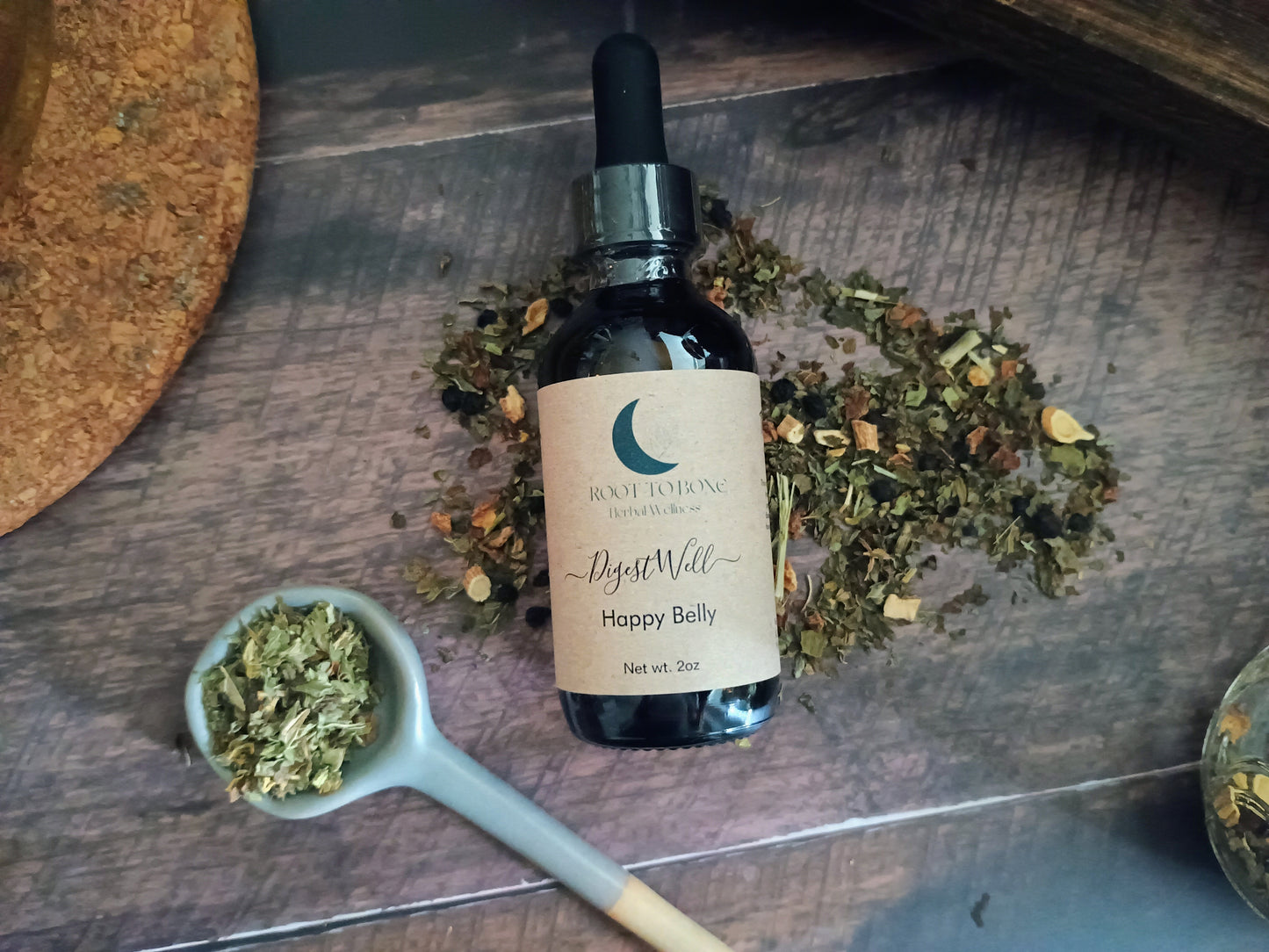 Bottle of 'Happy Belly' with dried herbs on a wooden surface