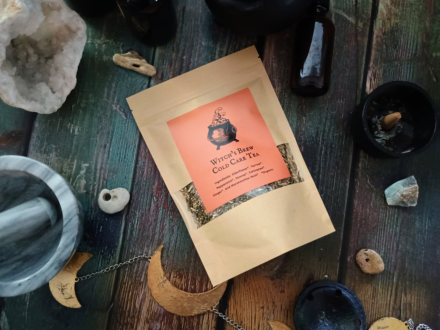 Witch Brew Cold Care Tea package on a wooden surface with mystical items.