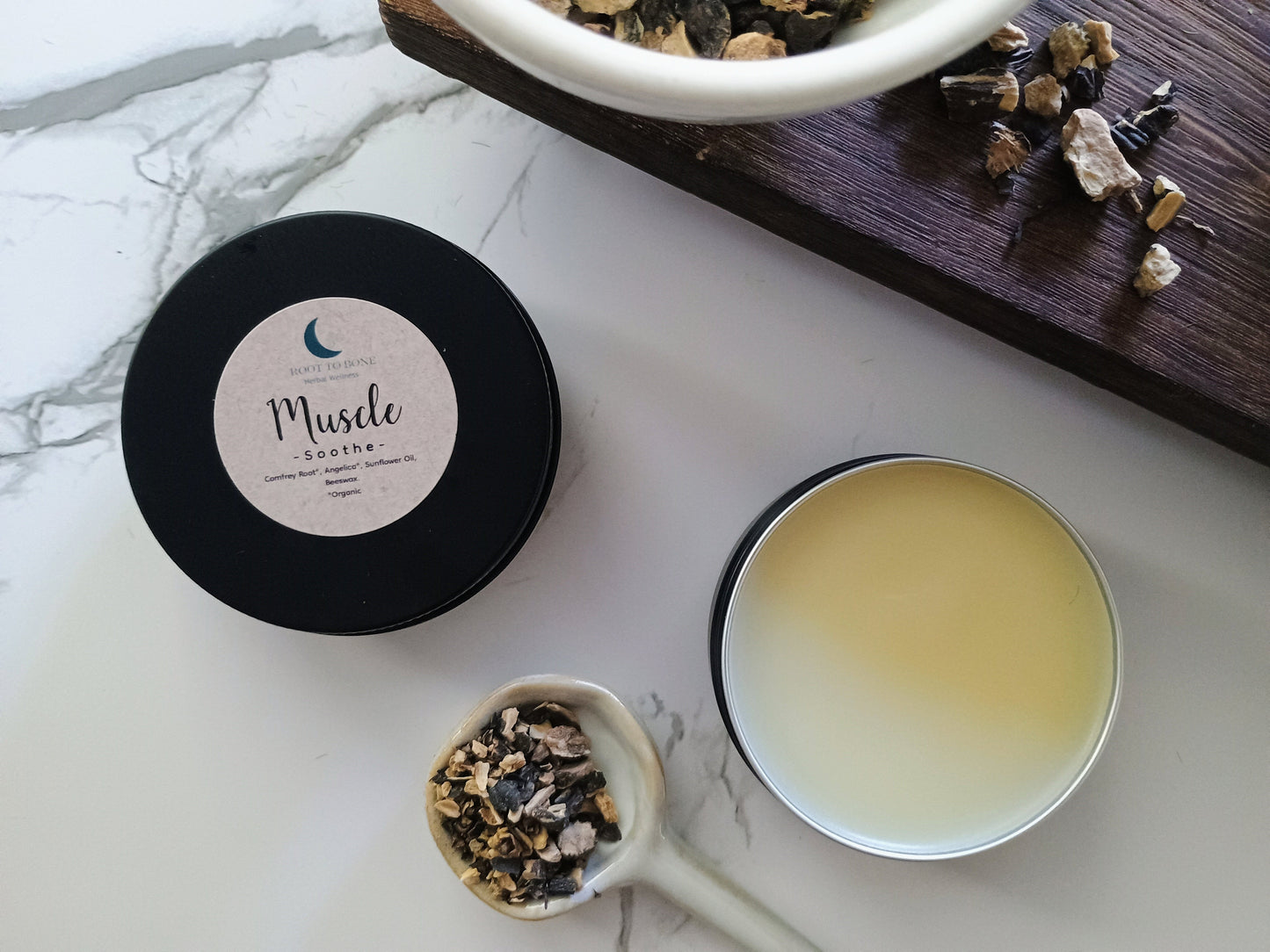 herbal salve and roots on a marble and wood surface