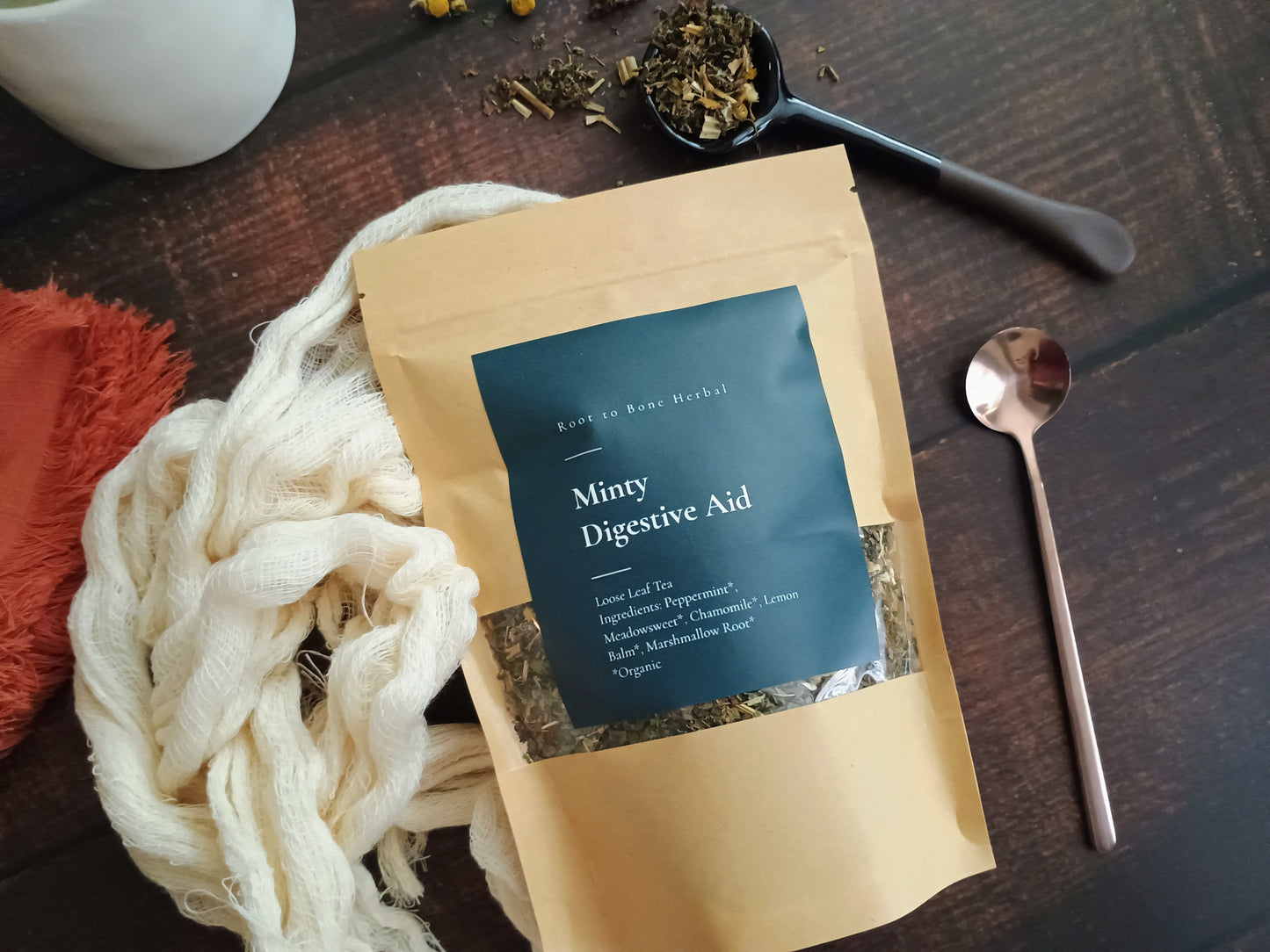 Minty Digestive Aid package on a wooden surface with a spoon and tea leaves.