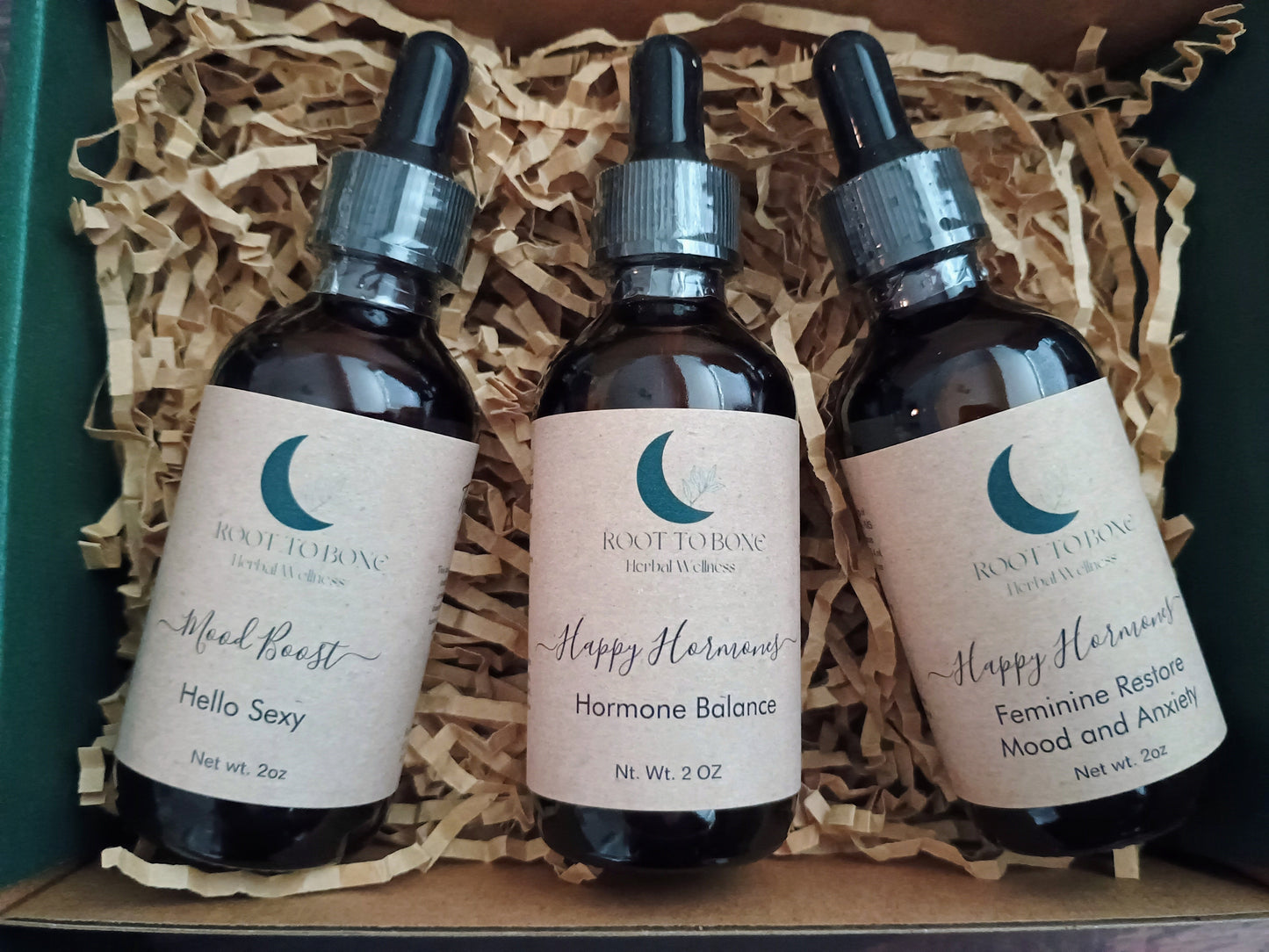 Three bottles of Root to Bone Herbal Remedies on a wooden surface with straw-like material.