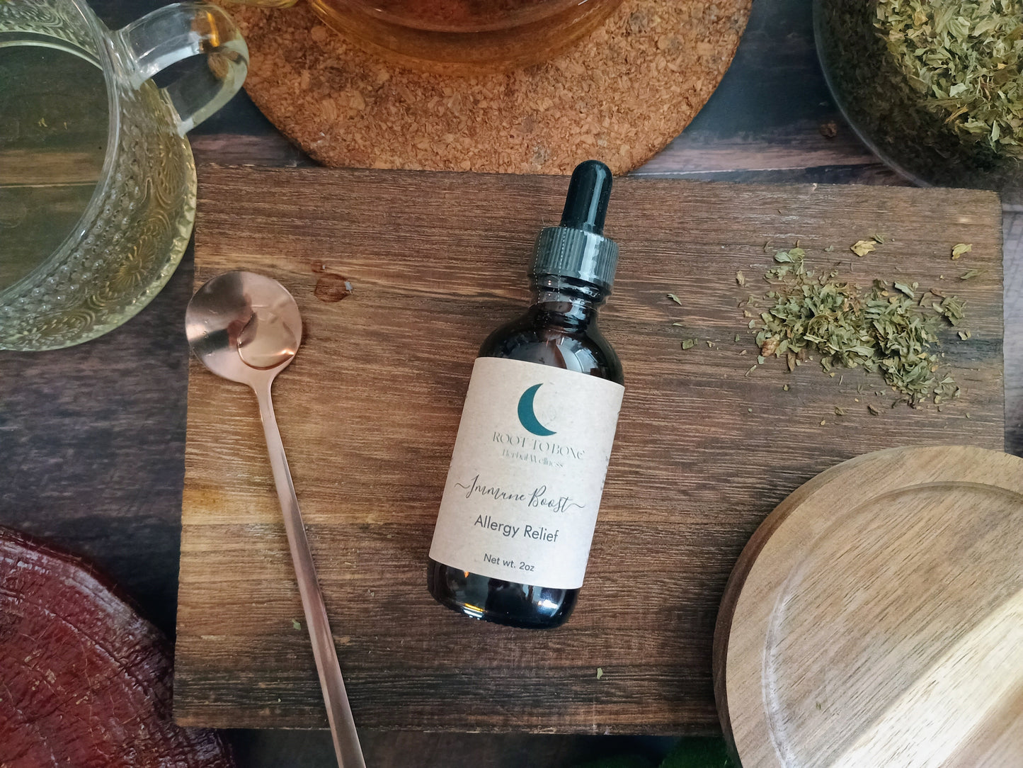 Bottle of tincture on a wooden surface with herbs and a teacup in the background