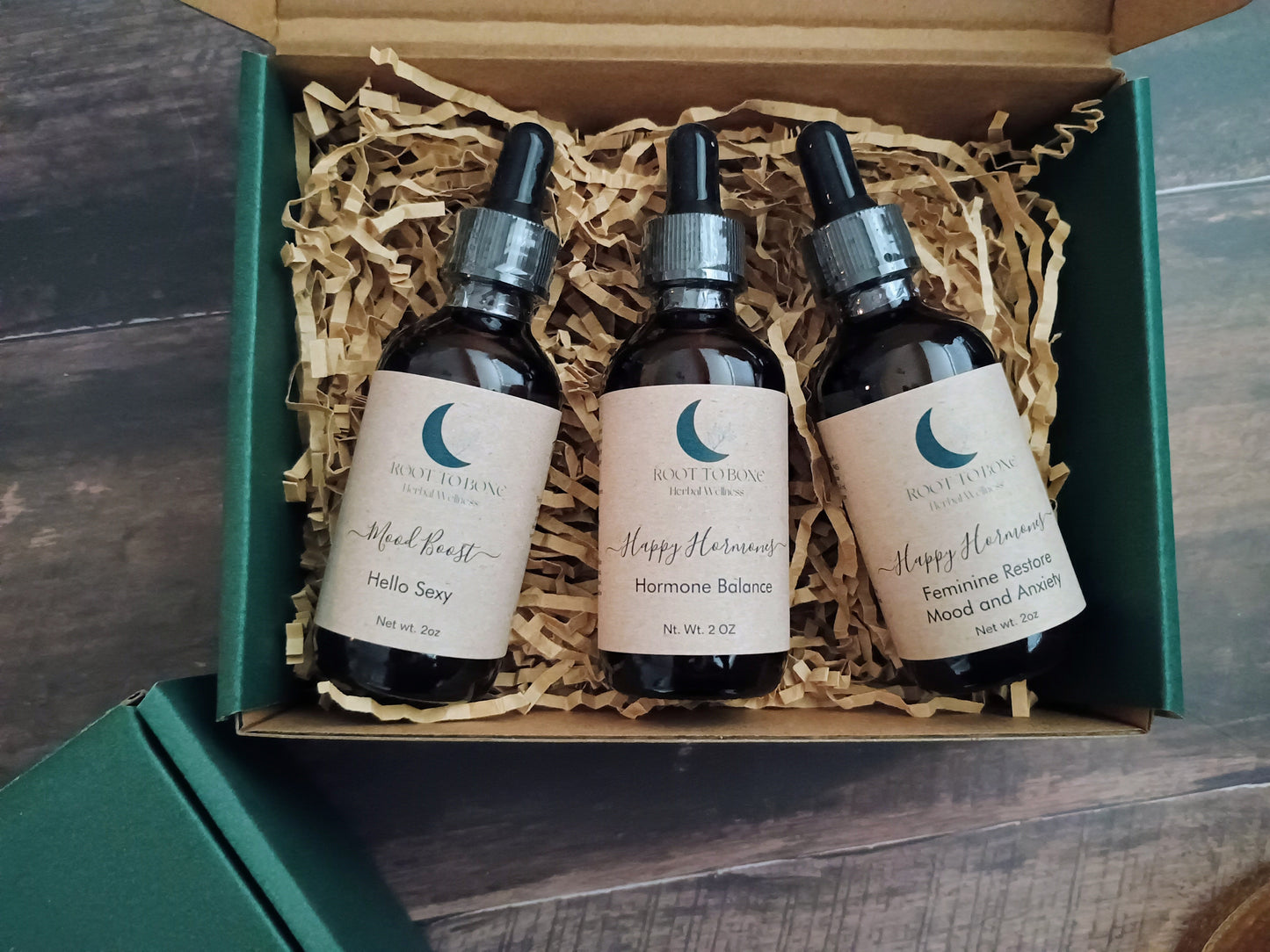 Three bottles of tinctures in a box with visible branding on a wooden surface