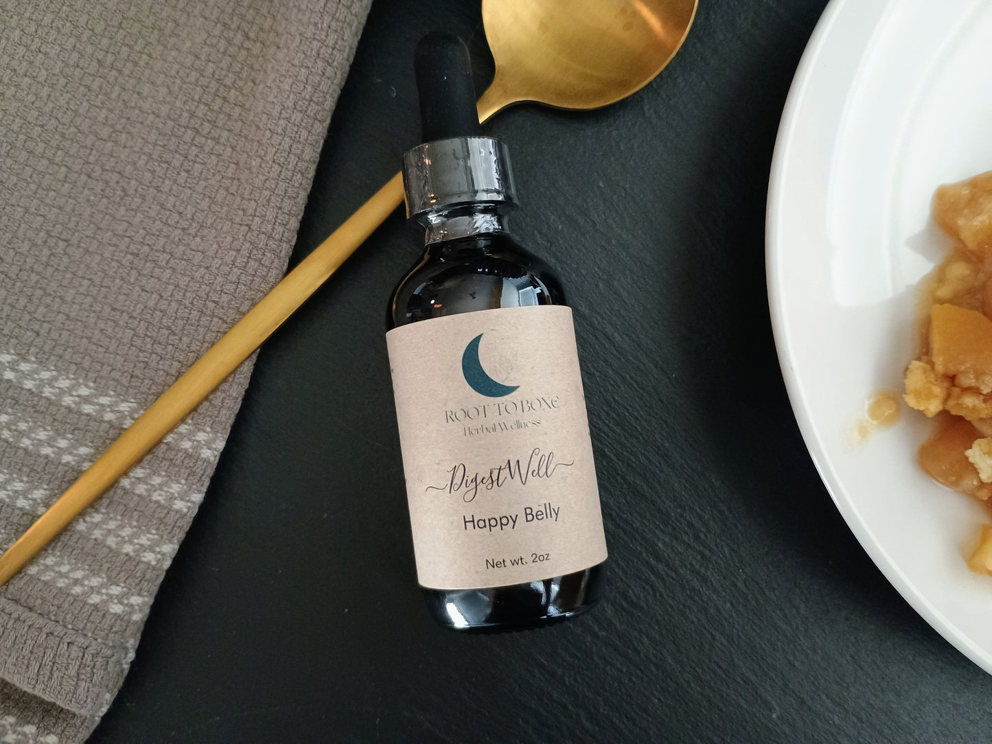 Bottle of 'Happy Belly' supplement on a dark surface with a spoon and plate in the background