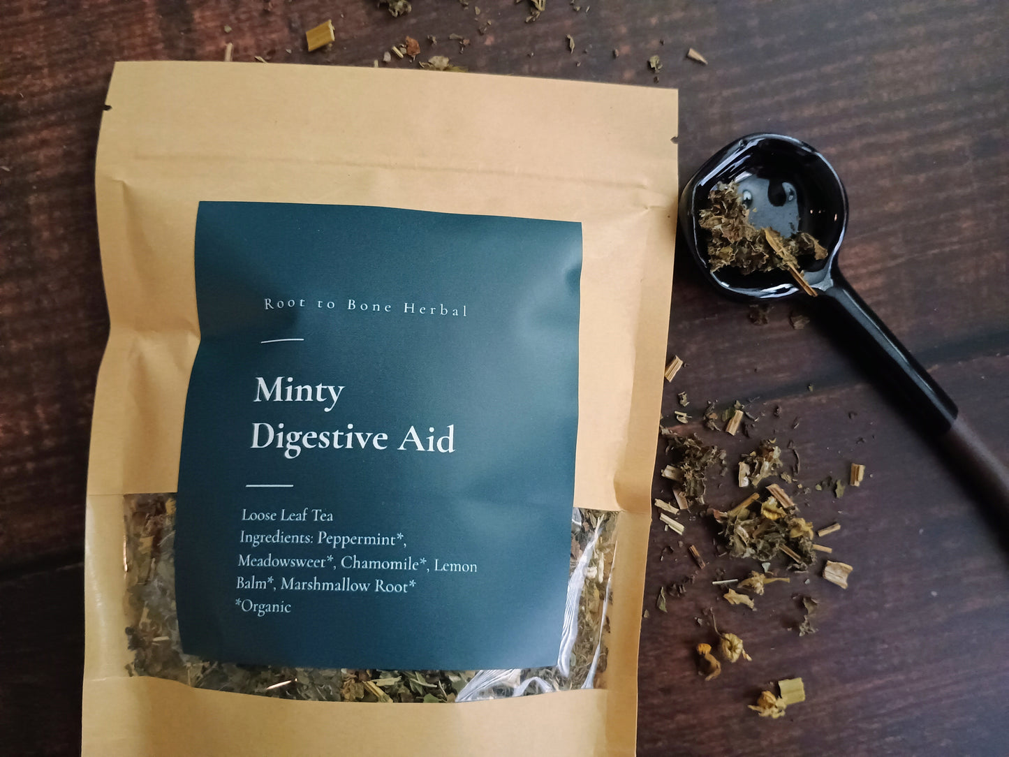 Tea package labeled 'Minty Digestive Aid' on a wooden surface with tea leaves.