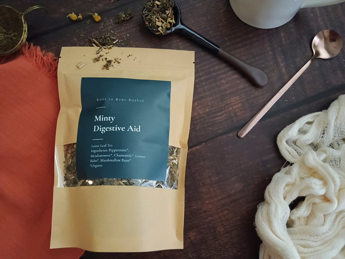 Tea package labeled ' digestive aid' on a wooden surface with a spoon and tea leaves.