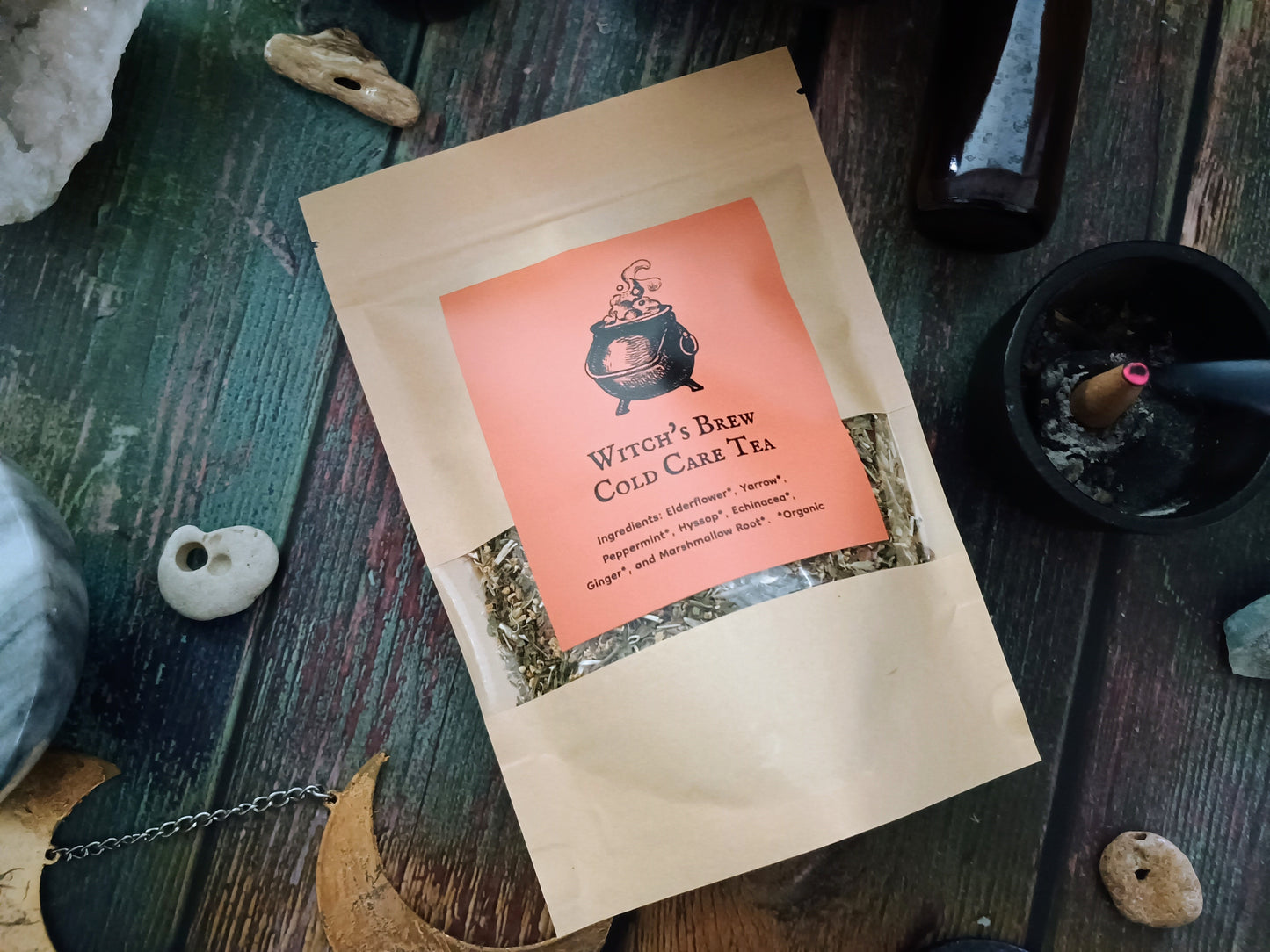 Witch's Brew Cold Care Tea package on a wooden surface with decorative elements.