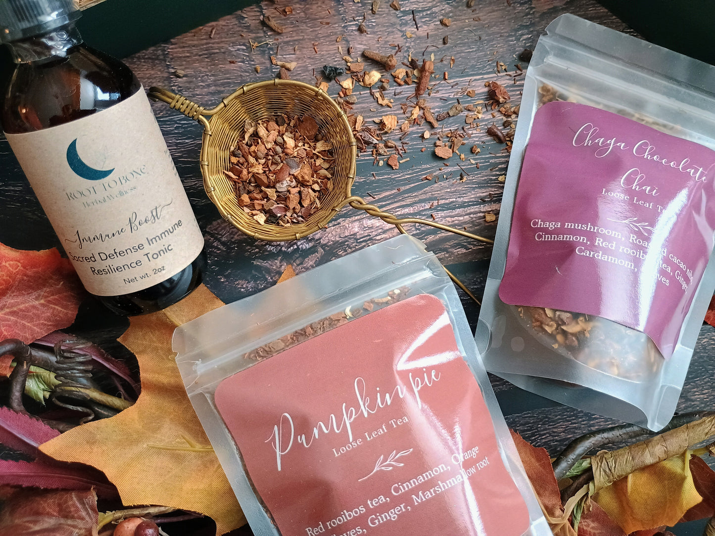 Tea packaging and herbs on a wooden surface with autumn leaves.