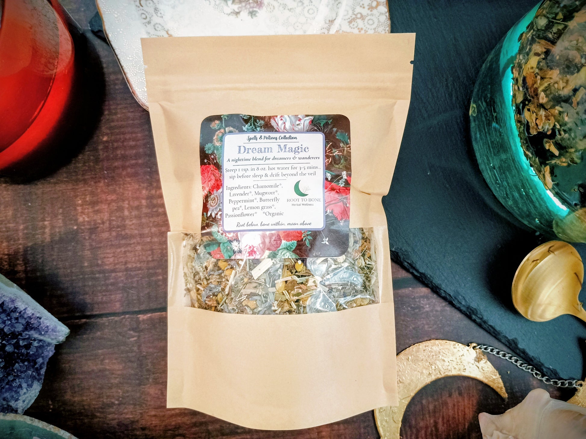 Bag of dried herbs labeled 'Dream Magic' on a wooden surface with a teacup and spoon.