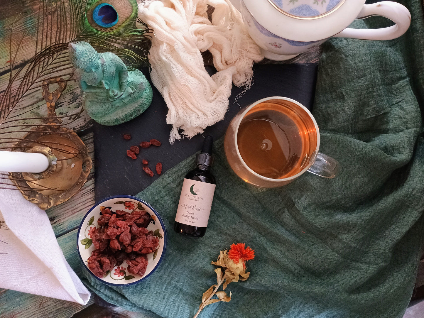 Tea cup, bottle, and dried herbs on a table with a green cloth