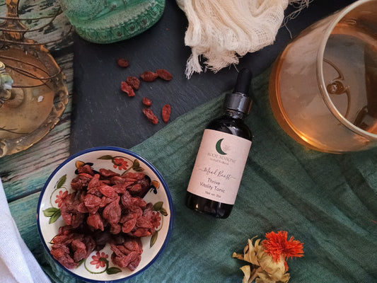 Bottle of tincture on a table with dried herbs and a candle