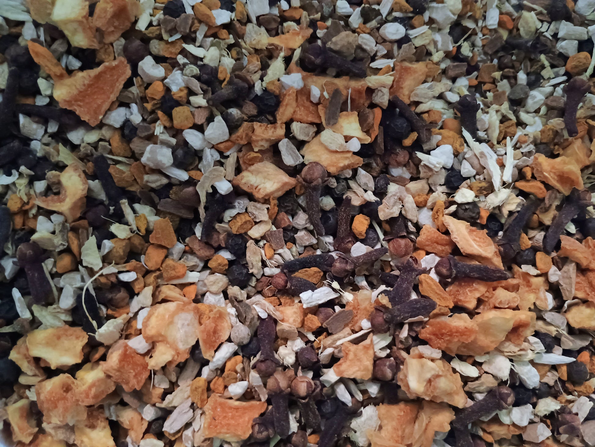 Mixture of dried herbs and spices including orange peels, black tea leaves, and white flowers.