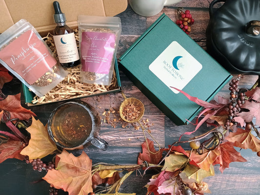 Herbal products and a green box with a brand logo on a wooden surface with autumn leaves.