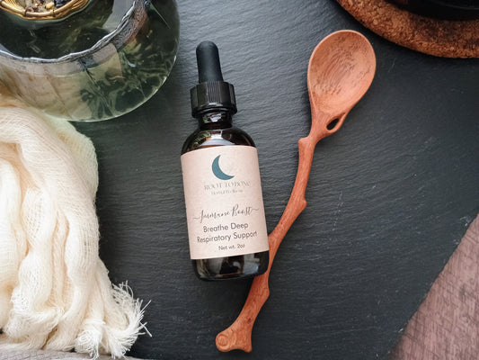 Bottle of respiratory support supplement on a dark surface with a wooden spoon and towel.