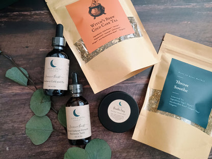 Herbal tea packages and bottles on a wooden surface with green leaves.