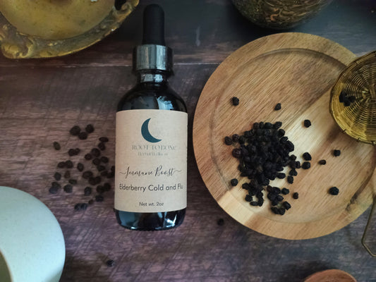 Bottle of 'root to bone Herbal' elderberry cold and flu syrup on a wooden surface with dried elderberries.
