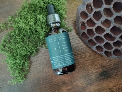 A small amber glass dropper bottle with a dark teal label sits on a wooden surface, styled with green moss on the left and a brown honeycomb pod on the right. The label shows the brand 'Root to Bone Herbal' and product name 'Po' 