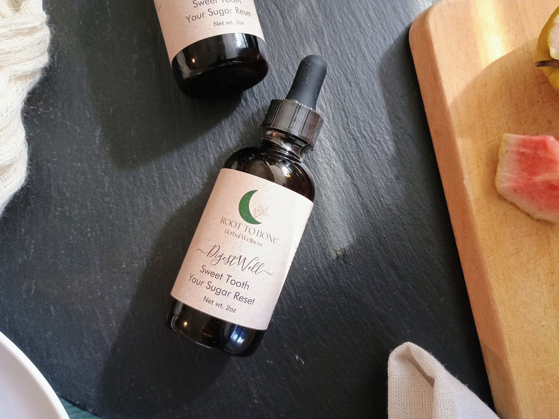 Bottle of 'Sweet Tooth' on a dark surface with a wooden cutting board in the background