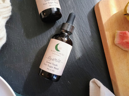 Bottle of 'Sweet Tooth' on a dark surface with a wooden cutting board in the background