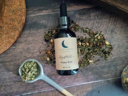 Bottle of 'Happy Belly' with dried herbs on a wooden surface