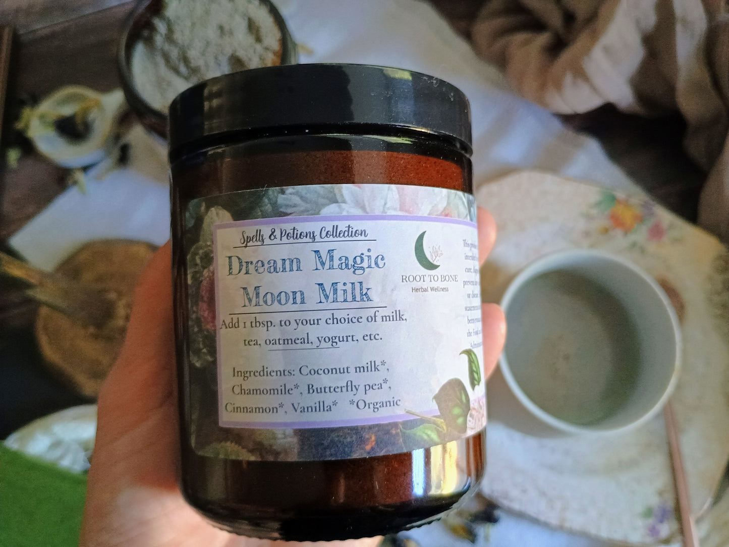Jar of 'Dream Magic Moon Milk' with a label held in front of a rustic background.