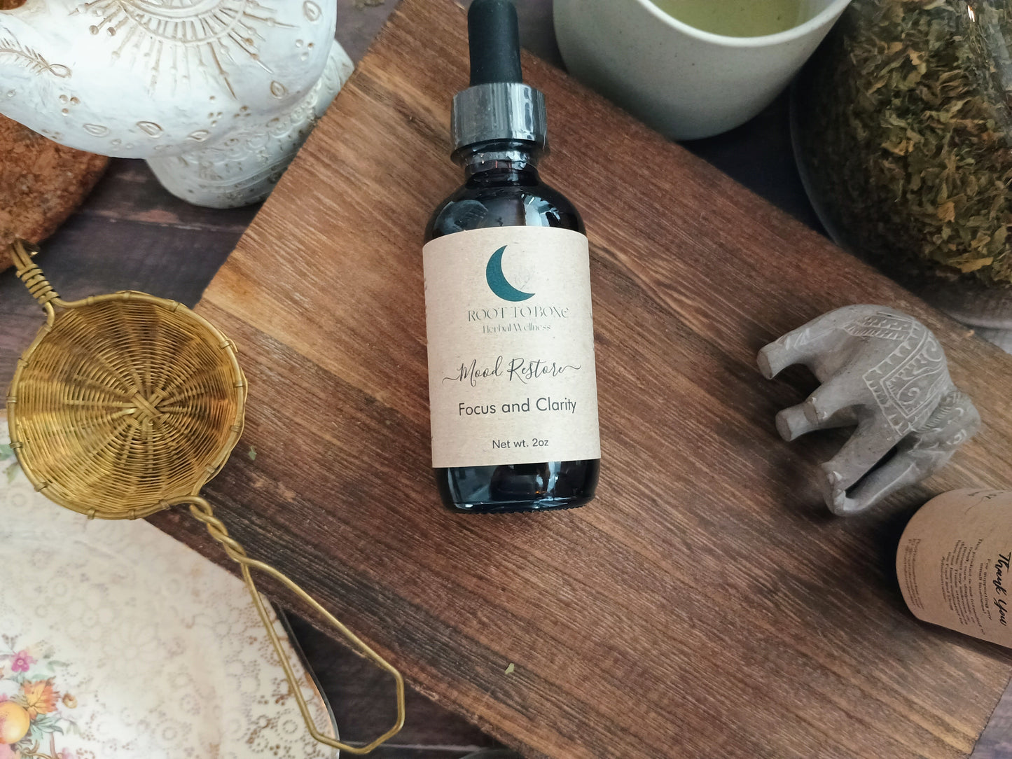 Bottle of 'Mood Restore focus and clarity' on a wooden surface with decorative items around
