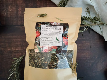 Herbal tea package labeled 'Protection Spell' on a wooden surface with rosemary.