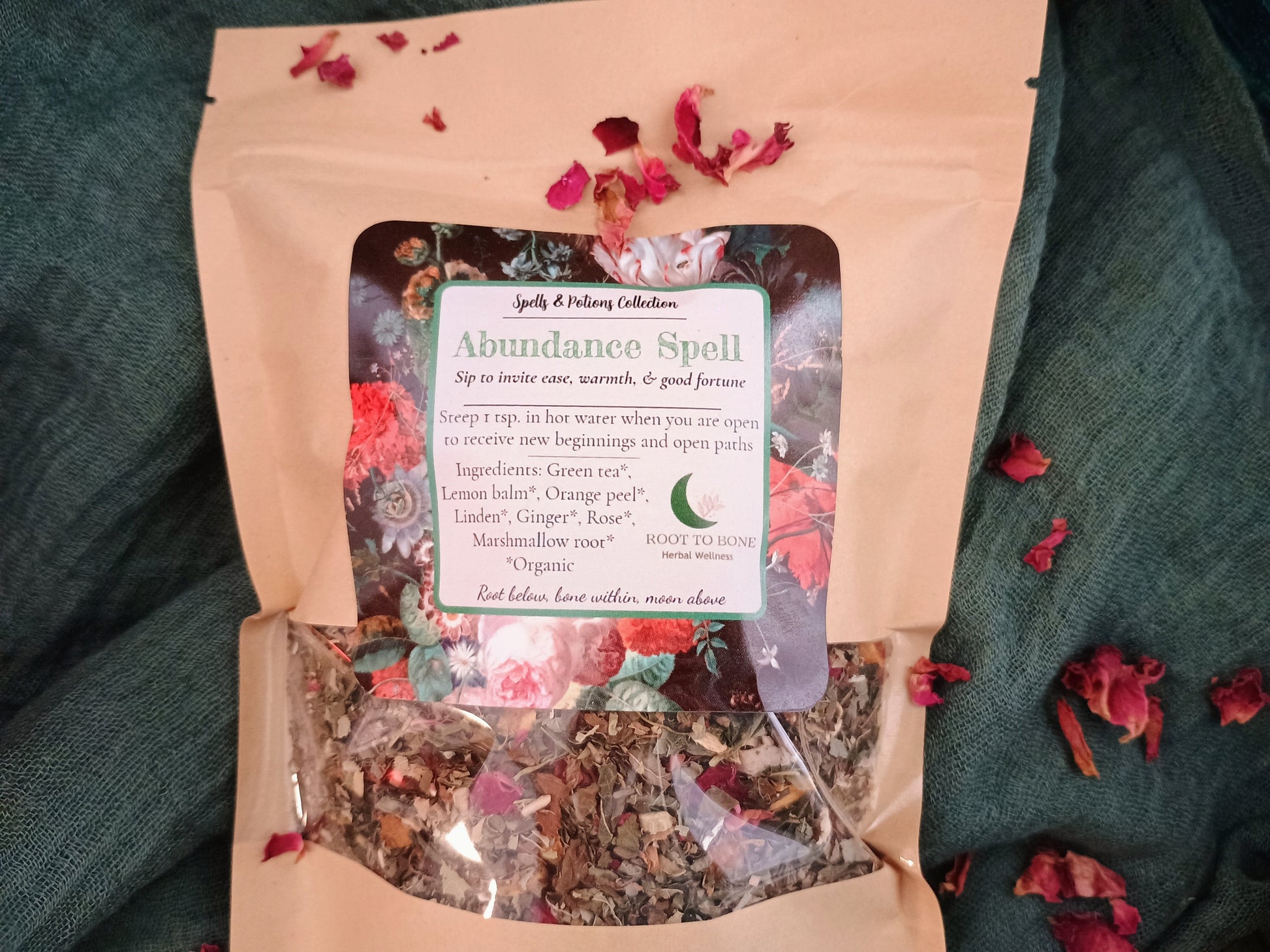 Herbal tea package labeled 'Abundance Spell' on a green fabric background