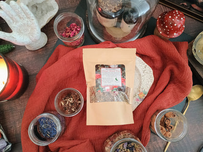 Herbal remedies and packaging on a red cloth with candles and crystals.