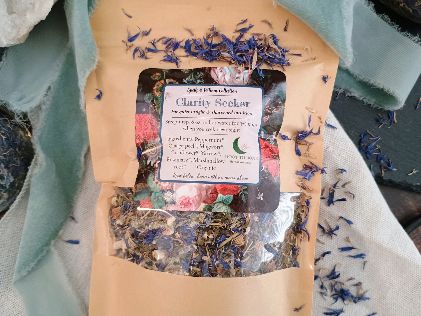Tea package labeled 'Clarity Seeker' with dried herbs on a textured fabric background