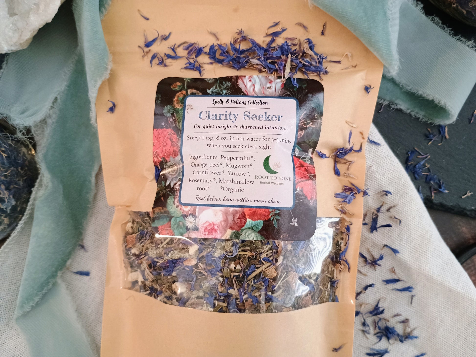 Tea package labeled 'Clarity Seeker' with dried herbs on a textured fabric background