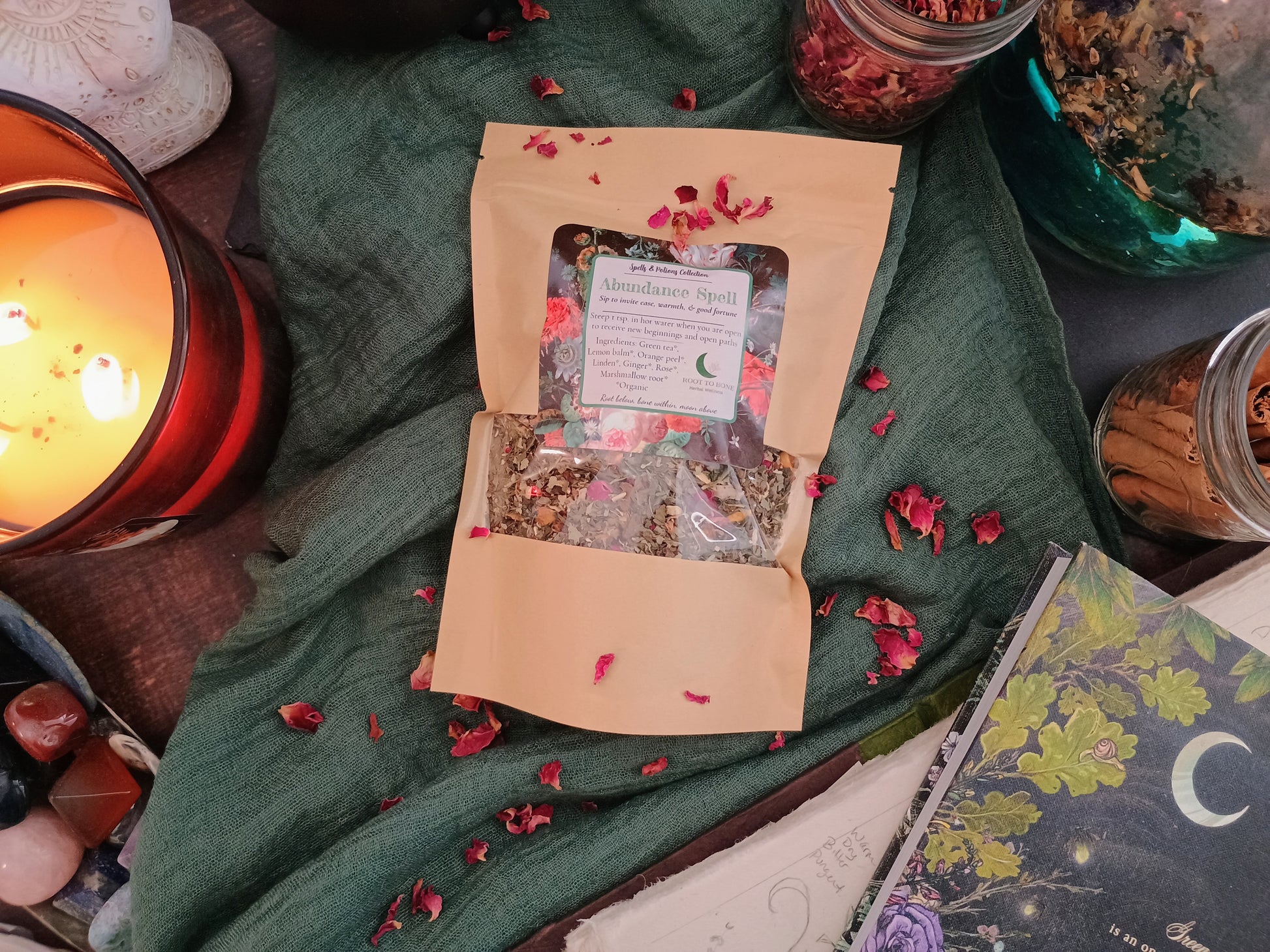 Open package of Abundance Spell tea with decorative elements on a green fabric background