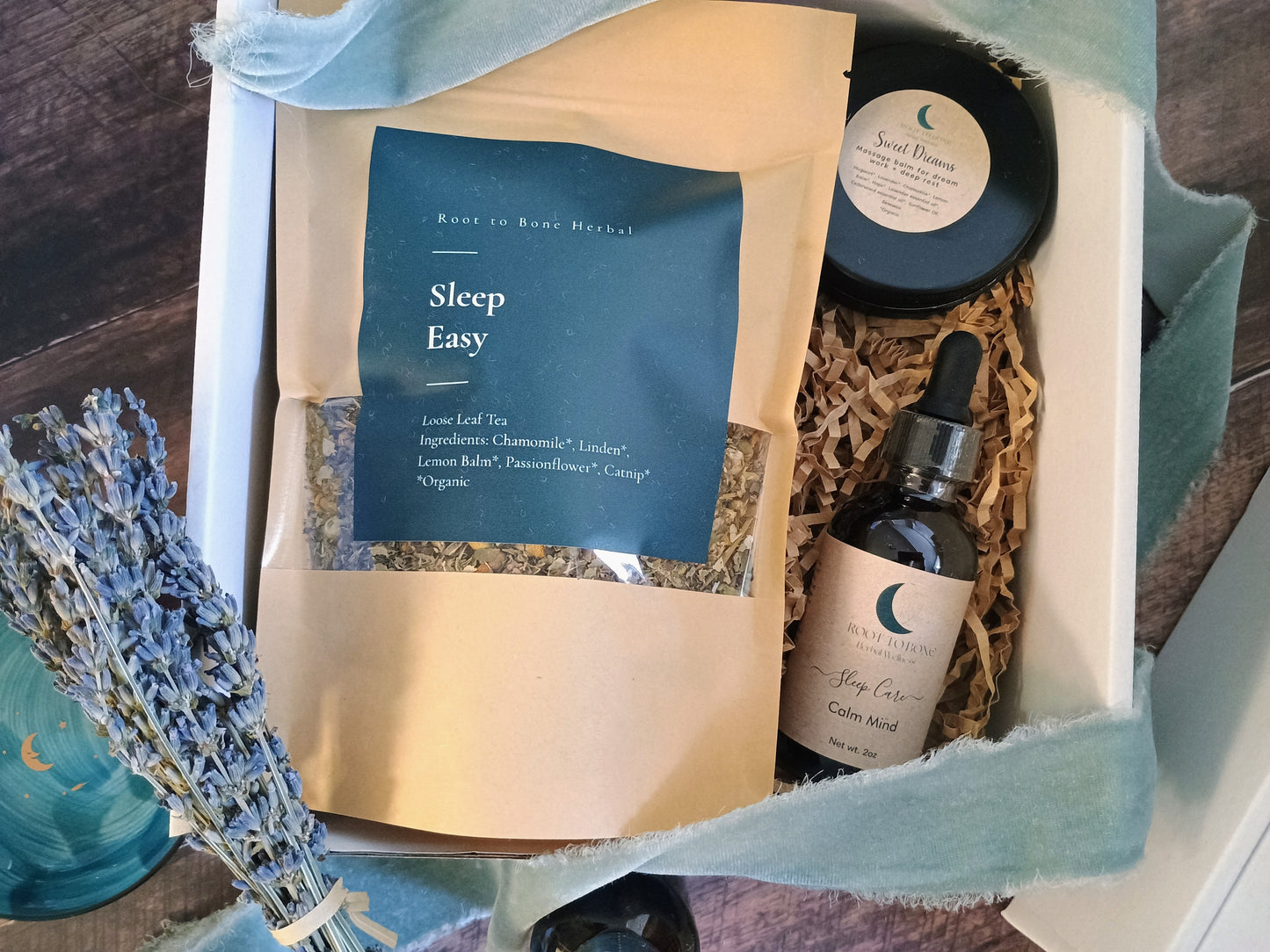 Gift set with sleep-themed products including a bottle, tea, and lavender on a wooden surface.