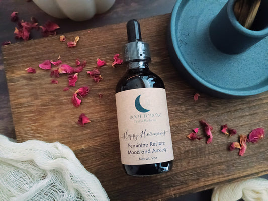 Bottle of 'Happy Hormones feminine restore' serum on a wooden surface with dried flowers and a blue palo santo holder