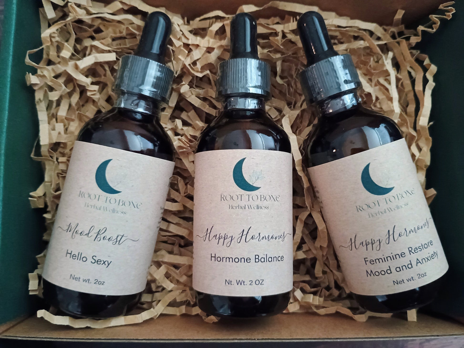 Three bottles of Root to Bone Herbal Remedies on a wooden surface with straw-like material.