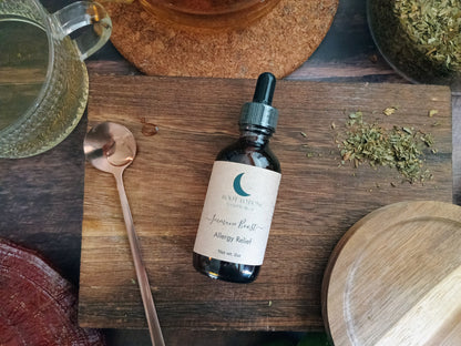 Bottle of tincture on a wooden surface with herbs and a teacup in the background