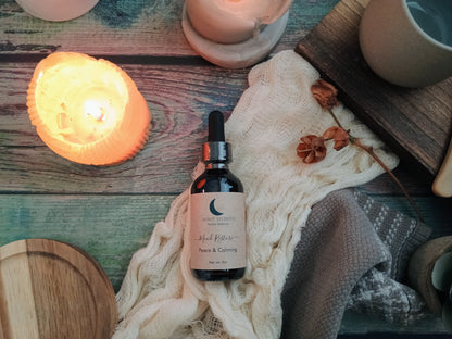 Bottle of 'Root to Bone Herbals' product on a textured surface with candles and wooden items.