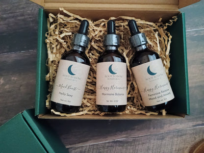 Three bottles of tinctures in a box with visible branding on a wooden surface