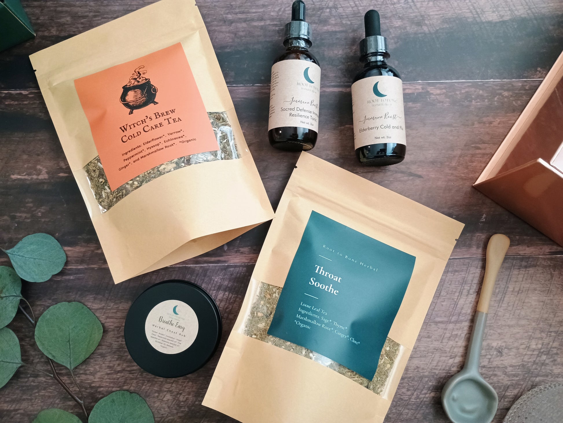 Herbal tea packages and bottles on a wooden surface with green leaves.