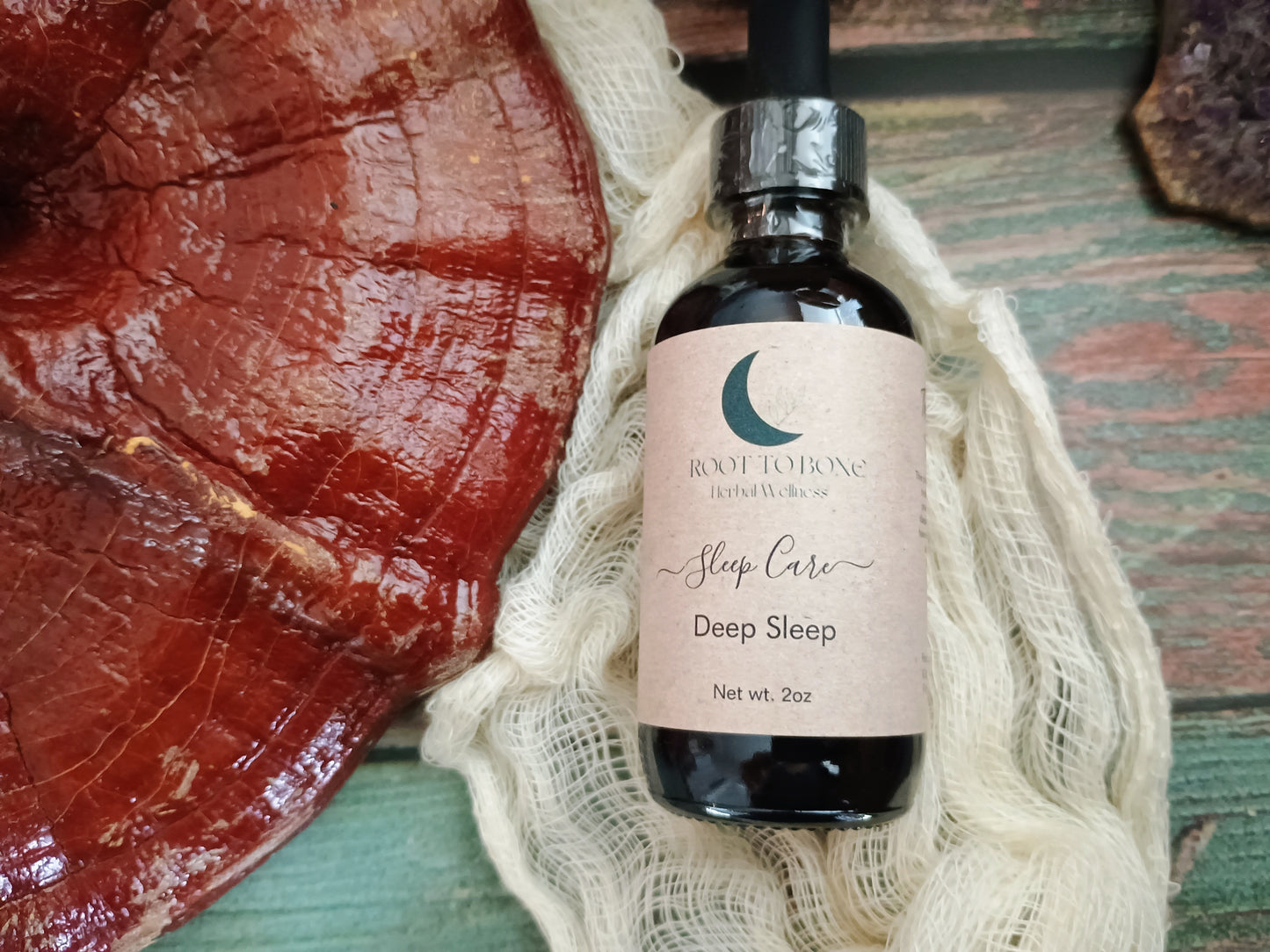 Bottle of 'Sleep Care Deep Sleep' product by Root to Bone on a textured surface with reishi mushroom.