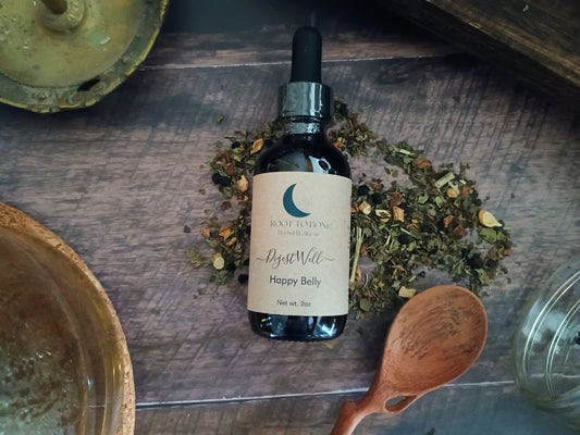 Bottle of 'Happy Belly' tincture with a wooden spoon and dried herbs on a rustic surface