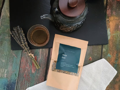 Tea package labeled 'Sleep Easy' on a wooden surface with a teapot and lavender.
