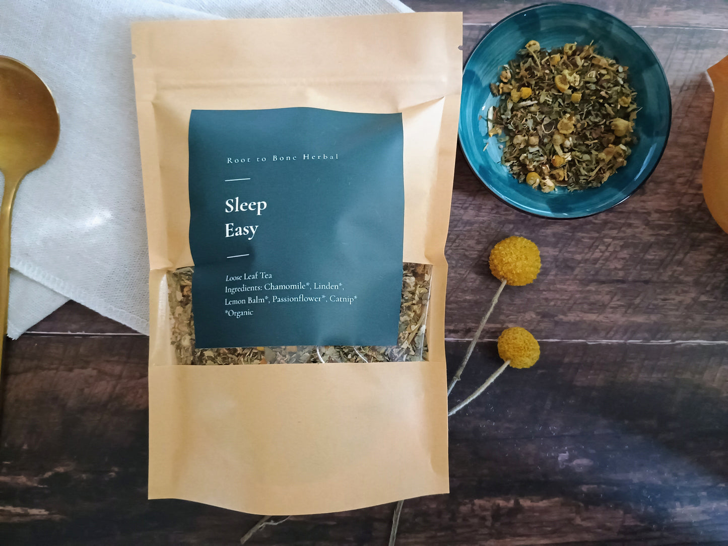 Sleep easy herbal tea package on a wooden surface with a bowl of tea leaves.