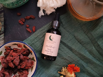 Bottle of tincture with dried herbs on a textured surface